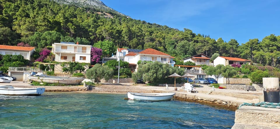 Šljunčana obala s drvenom brodicom, kamenim kućama i borovima — Eva Apartman, Kućište