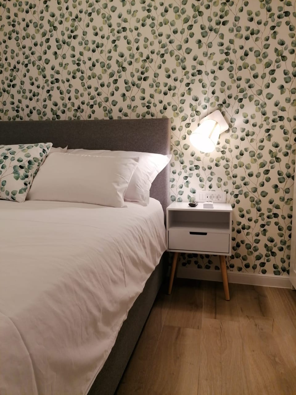 Bračni krevet s bijelim noćnim ormarićem i botaničkom tapetom — Eva Apartman, Kućište