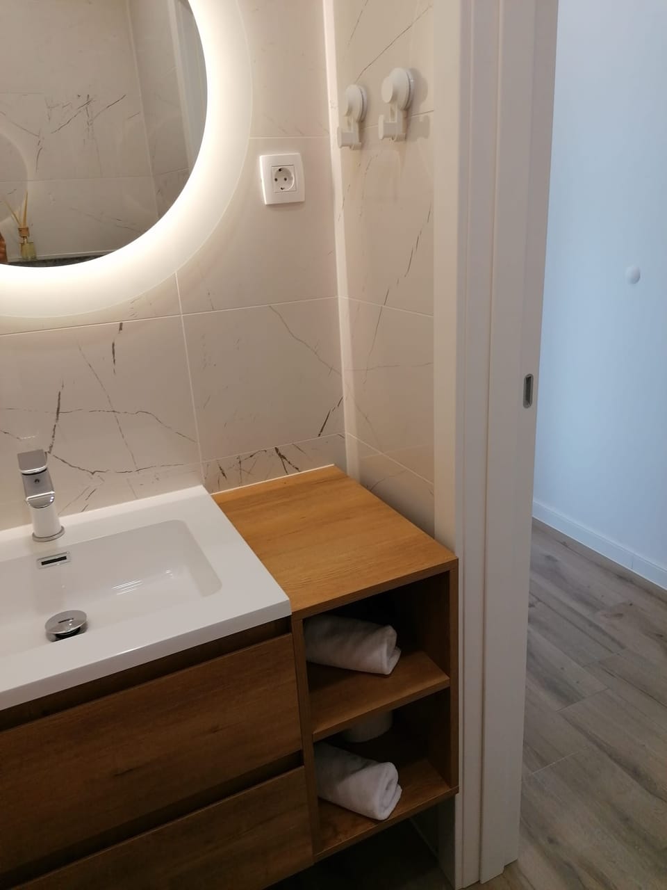 Umivaonik s drvenim ormarićem i složenim ručnicima — Eva Apartman, Kućište