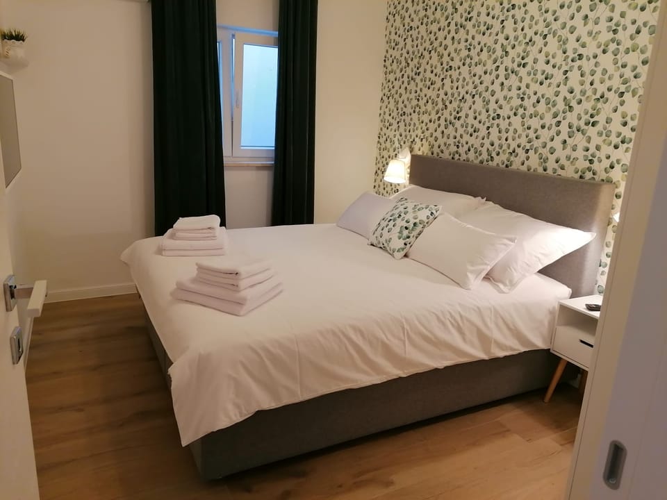 Bračni krevet sa svježim ručnicima i prozorom s pogledom na vrt — Eva Apartman, Kućište