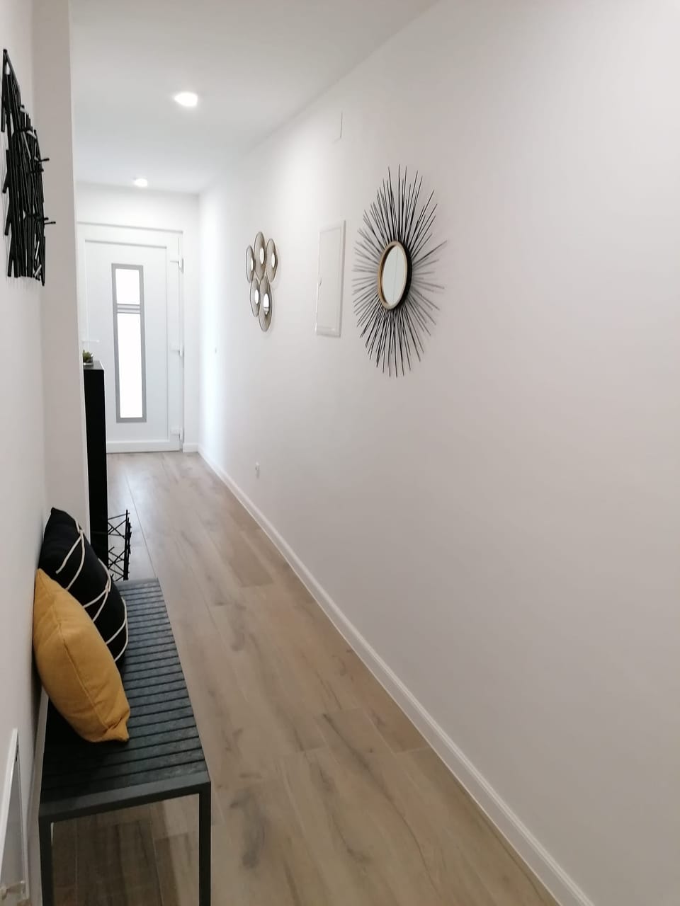 Svijetli ulazni hodnik s drvenim podom i zrcalom u obliku sunca — Eva Apartman, Kućište