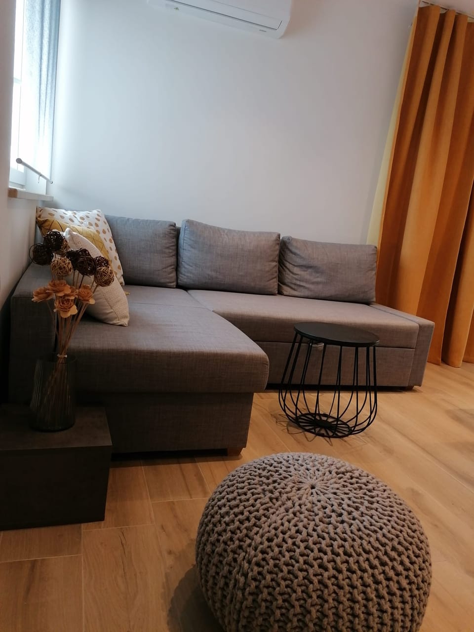 Siva kutna sofa s pomoćnim stolićima i pletenim tabureom — Eva Apartman, Kućište