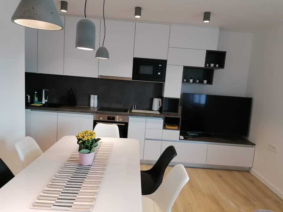 Kuhinja i blagovaonički stol ispod visećih svjetiljki — Eva Apartman, Kućište