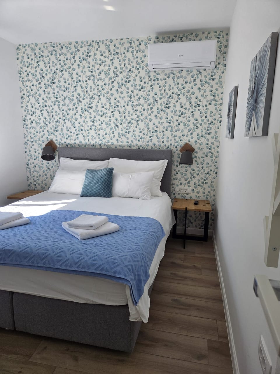 Bračni krevet s plavim prekrivačem i složenim ručnicima — Eva Apartman, Kućište