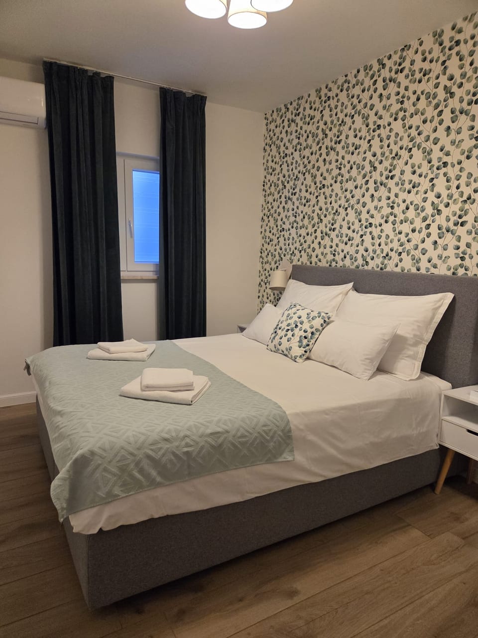 Bračni krevet sa zelenim prekrivačem uz prozor sa zavjesama — Eva Apartman, Kućište