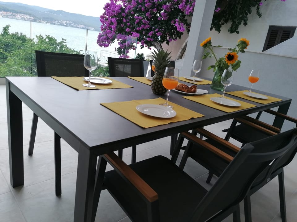 Vanjski blagovaonički stol ispod rascvjetane bugenvilije — Eva Apartman, Kućište